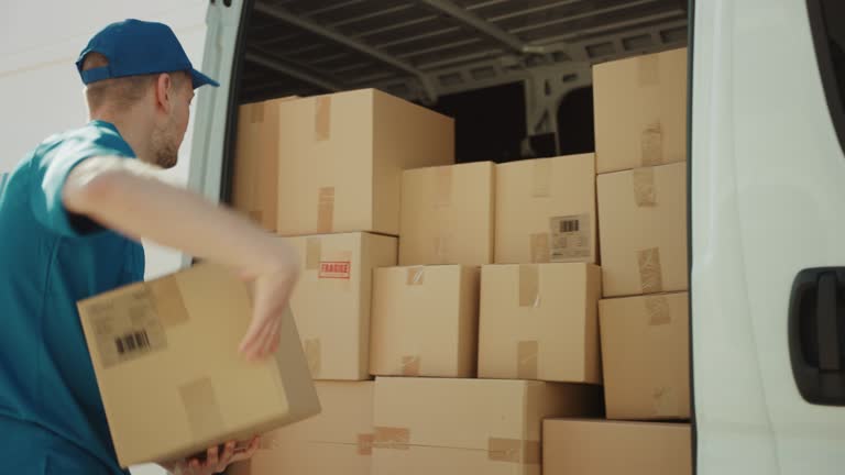 Courier Opens Delivery Van Side Door and Takes out Cardboard Box Package, Closes the Door and Goes on Delivering Postal Parcel.