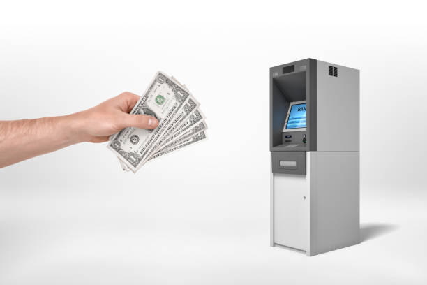 istock Man's hand holding dollar banknotes and reaching out for an ATM on a white background. 1176790677