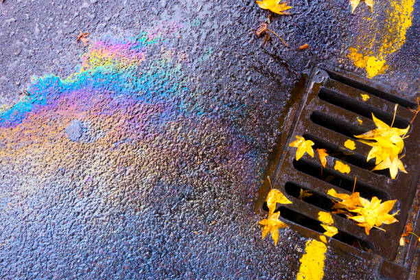 istock Oil Pollution Spill Running Down Guttering Drain on a Wet Day 1176791932