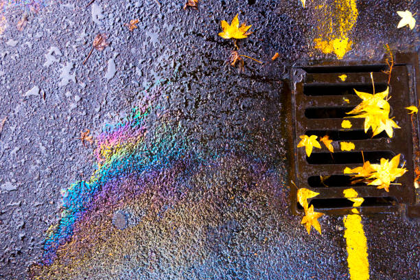 istock Oil Pollution Spill Running Down Guttering Drain on a Wet Day 1176792017
