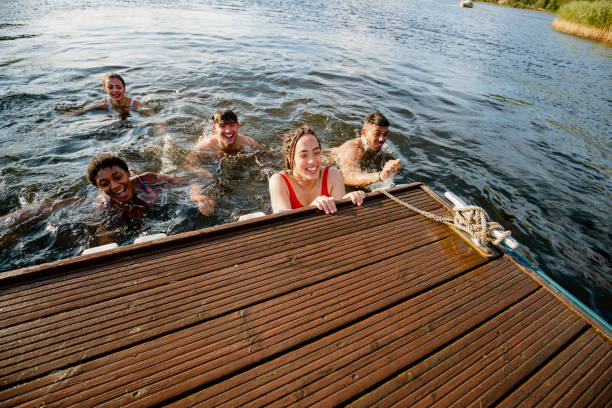 Help Us Out A group of young multi ethnic friends swimming to the pier on Derwent Water in The Lake District in Cumbria derwent water stock pictures, royalty-free photos & images