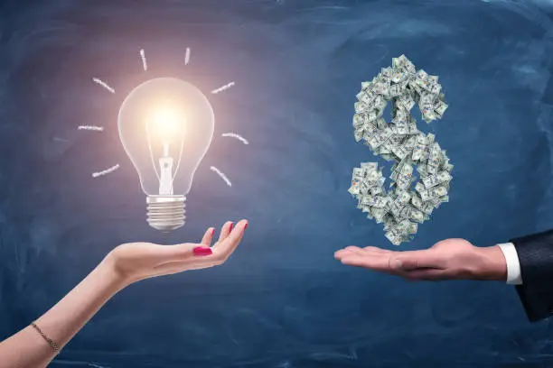 Photo of A female and a male hands holding a large bright light bulb and a dollar sign made of many money bills.