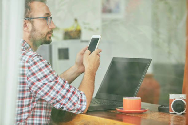 istock Modern bearded man using cellphone and drinking coffee with laptop. 1176794199