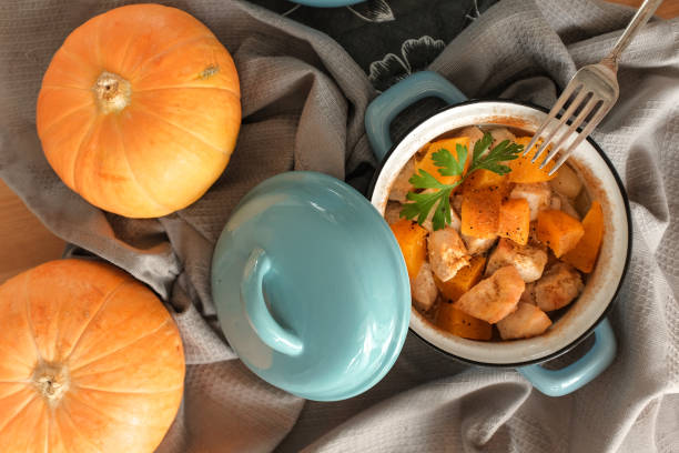 Roast pumpkin and chicken with spices in a blue pan on a wooden table, top view. Thanksgiving concept.daylight