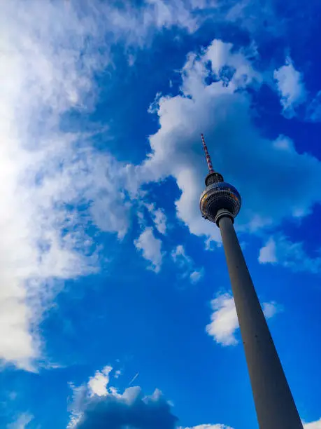 Berlin TV tower. View from below. Blue sky and curly clouds.