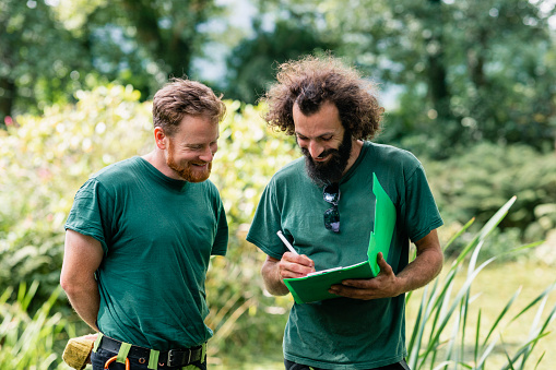 Two landscape gardeners making notes on clipboard