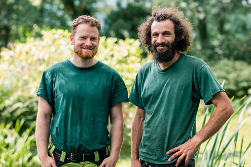 Two men wearing green t shirts looking at camera, landscape gardening, agricultural workers
