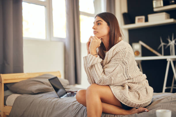 istock Woman sitting on bed in bedroom. 1176806107