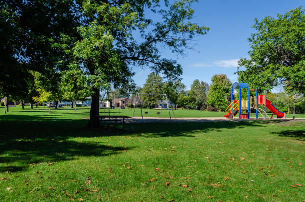 Neighborhood park and playground area on a summer day with shade and a blue sky, Neighborhood park and playground area on a summer day with shade and a blue sky, swing play equipment stock pictures, royalty-free photos & images