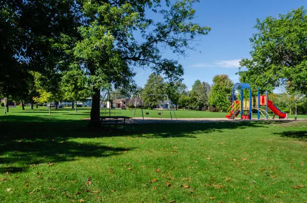Photo of Neighborhood park and playground area on a summer day with shade and a blue sky,