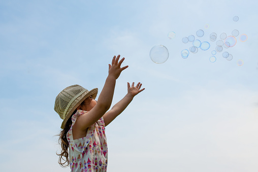 Toddler girl reaching for soap bubbles