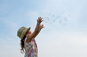 Toddler girl reaching for soap bubbles