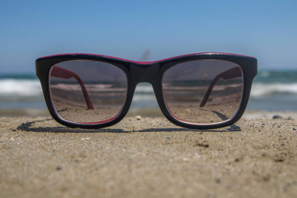 istock Sunglasses on the sand by the sea 1176809969