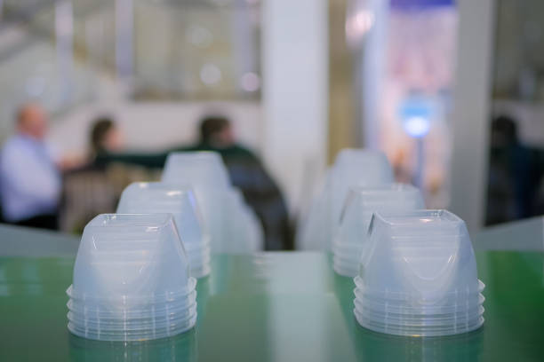 Stack of polypropylene food containers on conveyor belt of automatic plastic injection molding machine at fabric, exhibition, trade show. Manufacturing, industry, automated technology concept