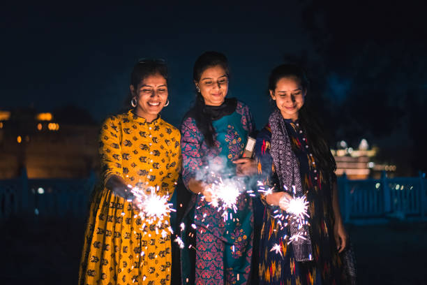 Three young Indian women with bengal fireworks, Udaipur, India Three young Indian women with bengal fireworks, celebrating Indian Festival Diwali. Three girls are looking at fireworks. diwali photos stock pictures, royalty-free photos & images