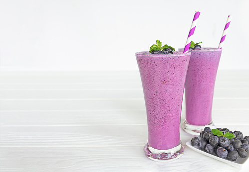 Blueberry smoothies juice a tasty healthy drink in a glass drink the morning on white wooden background.