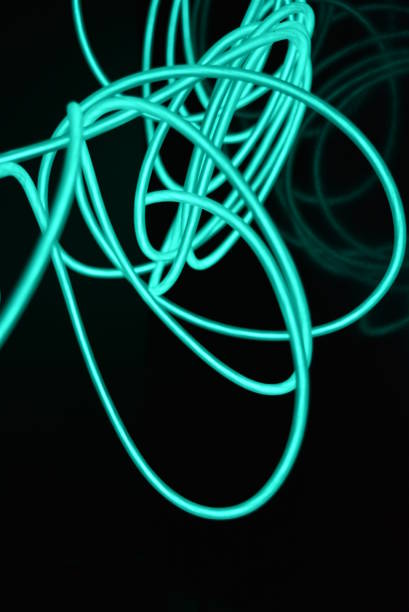 Original wrapped photos of luminous wires, bright colors. I placed differently coils of light wire so that there were different images and backgrounds. I can easily easily decorate any of your things with this wire in a different light. All these photos were taken on the Severny massif, the city of Dnipro, the country of Ukraine. cables brillantes inusuales hechos de material de color turquesa que brilla por la noche. los caóticos cables azulcielo, los cables electroluminiscentes de guía de luz, la electroluminiscencia se encuentran en una superficie negra brillante.