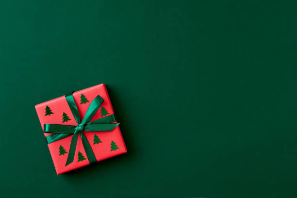 confezione regalo rossa su sfondo verde. cartolina di natale. lay piatto. visualizzazione superiore con spazio per il testo - christmas gift foto e immagini stock