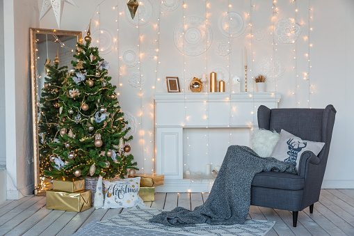 Modern design room in light colors decorated with Christmas tree and decorative elements.