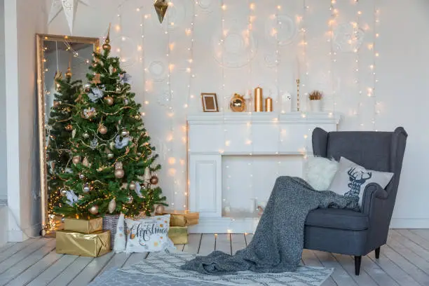 Photo of Modern design room in light colors decorated with Christmas tree and decorative elements