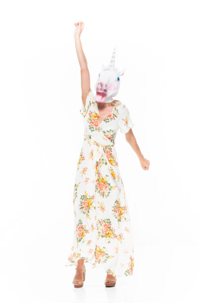 front view / looking at camera / full length of 20-29 years old adult blond hair / long hair caucasian young women standing in front of white background wearing mask - disguise / dress / long dress who is bizarre / wearing a unicorn mask / horse - 13520 imagens e fotografias de stock