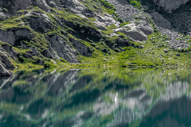 istock Rocky hillside reflected open water of Lac du Brevent 1176825175