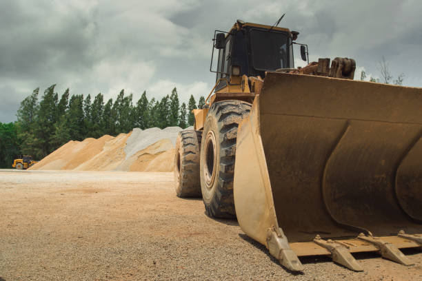 escavatori e macchinari pesanti nei lavori di movimento della pietra in un'estrazione di pietra di cava per la sua trasformazione in ghiaia, escavatore in una miniera a cielo aperto. - loading wheel mining equipment foto e immagini stock