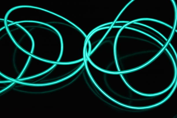 Chaotic wire, original wound photos of luminous wires, bright inexpressible colors. I placed differently coils of light wire so that there were different images and backgrounds. All these photos were taken on the Severny massif, the city of Dnipro, the country of Ukraine. cables brillantes inusuales hechos de material de color turquesa que brilla por la noche. los caóticos cables azulcielo, los cables electroluminiscentes de guía de luz, la electroluminiscencia se encuentran en una superficie negra brillante.