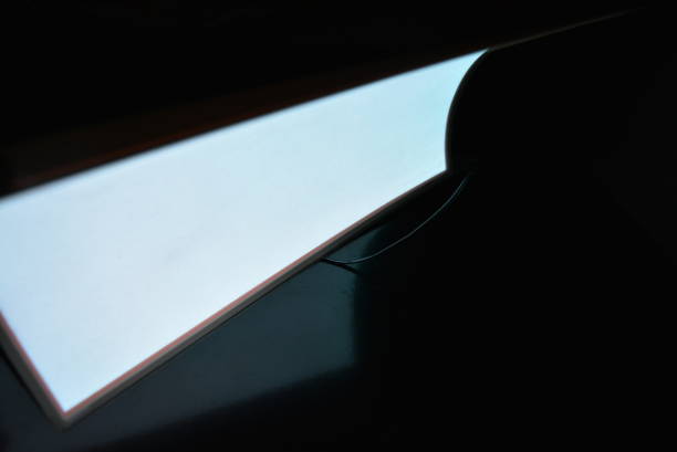 istock Very bright and luminous A4 electroluminescent paper with an  coating is located in different flatnesses on a pristine glossy surface with a female hand. Excellent color substrate, uniform glow. 1176827108