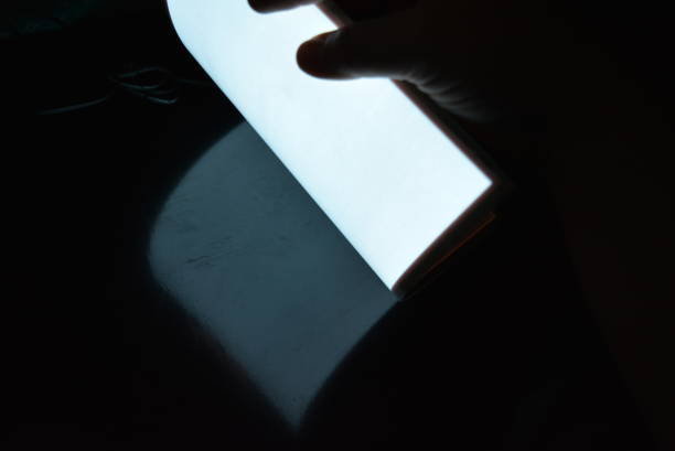 istock Very bright and luminous A4 electroluminescent paper with an  coating is located in different flatnesses on a pristine glossy surface with a female hand. Excellent color substrate, uniform glow. 1176827213