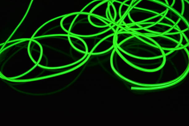 istock Toxic green luminous electroluminescence wires with different shapes and structures. A web of lime electroluminescent fiber, el wires and unusual circles located on a black glossy surface. 1176827411