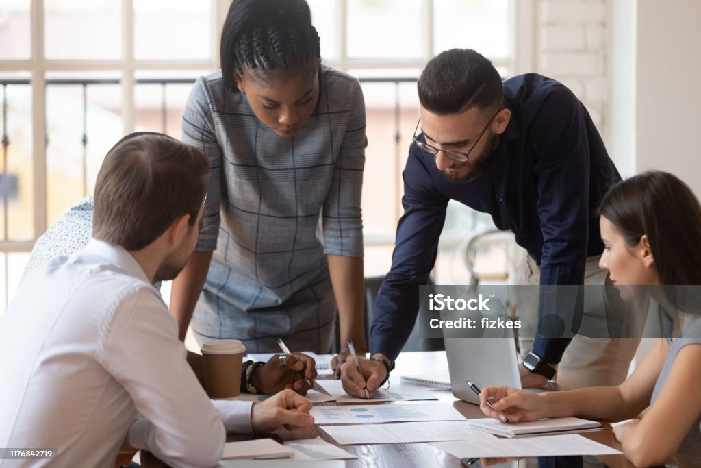 La gente del equipo de negocios corporativomultir centrado sin hacer una lluvia de ideas sobre el papeleo - Foto de stock de Trabajo en equipo libre de derechos
