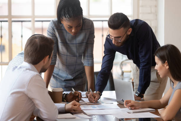 Focused multiracial corporate business team people brainstorm on paperwork Focused multiracial corporate business team people brainstorm on marketing plan financial report gather at office table meeting, diverse serious colleagues group discuss paperwork engaged in teamwork service department stock pictures, royalty-free photos & images