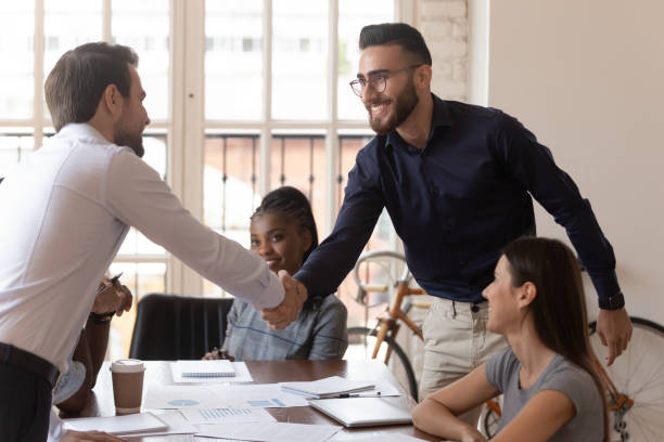 istock Two happy businessmen shake hands at group negotiation greeting 1176842730