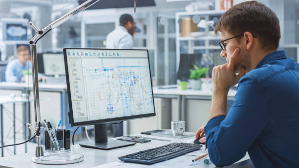 istock Over the Shoulder Shot of Engineer Working with CAD Software on Desktop Computer, Screen Shows Technical Drafts and Drawings. In the Background Engineering Facility Specialising on Industrial Design 1176842821