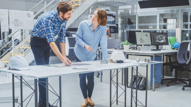 istock In Engineering Agency: Female Engineer and Male Technician Working on Design for Industrial Engine Prototype. Specialists Talk During Meetings, Work with Drawings. 1176842837