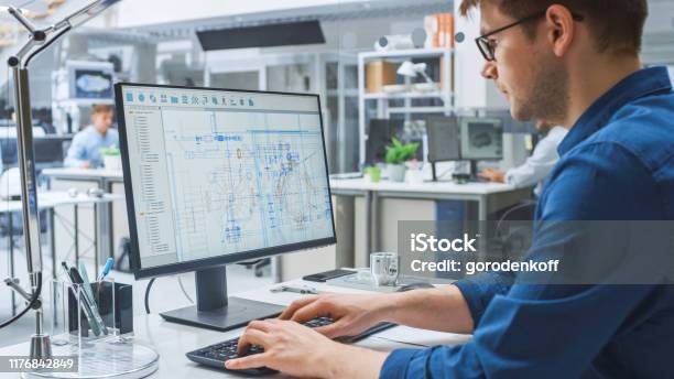 Over The Shoulder Shot Of Engineer Working With Cad Software On Desktop Computer Screen Shows Technical Drafts And Drawings In The Background Engineering Facility Specialising On Industrial Design Stock Photo - Download Image Now
