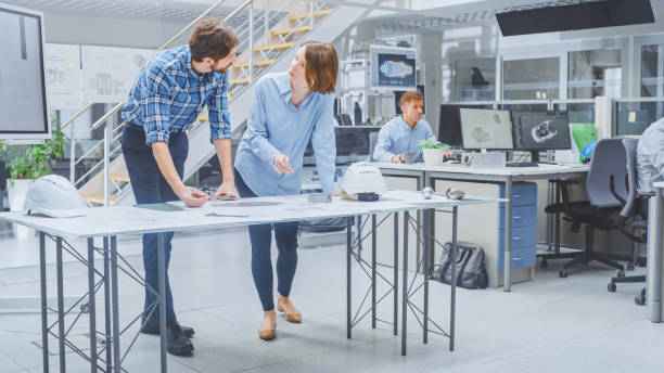 istock In the Busy Engineering Facility: Diverse Group of Engineers, Technicians, Working on Design for Industrial Engine Prototype. Specialists Talk During Meetings, Work with Drawings, Use Computers 1176842880