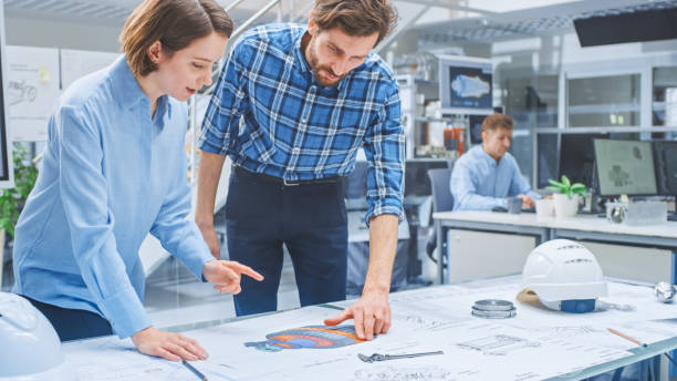 istock In the Busy Engineering Agency: Diverse Group of Engineers, Technicians, Specialists Working on Design for Industrial Engine Prototype. Professionals Talk, Work with Drawings, Use Computers 1176842892