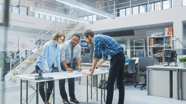 istock In the Industrial Engineering Facility: Two Architects and Chief Engineer, Discuss and Analyse Industrial Engine Prototype Drafts Using Conference Table. 1176842898