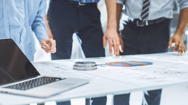 istock Industrial Engineering Facility: Close-up on Hands of Group of Engineers, Technicians and Specialists on a Meeting, Tracing Lines and Analysing Engine Design Technical Drafts Laying on the Table 1176842956