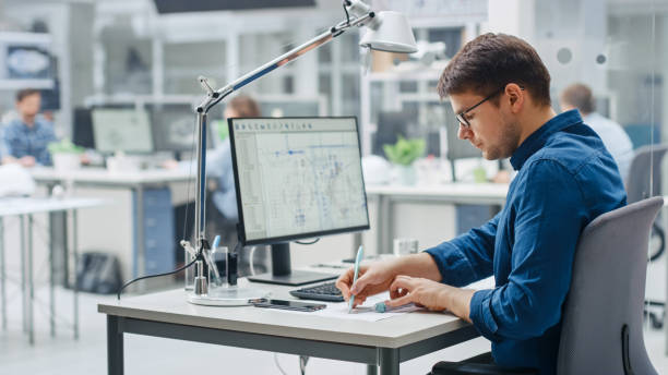 istock Over the Shoulder Shot of Engineer Working with CAD Software on Desktop Computer, Screen Shows Technical Drafts and Drawings. In the Background Engineering Facility Specialising on Industrial Design 1176843661