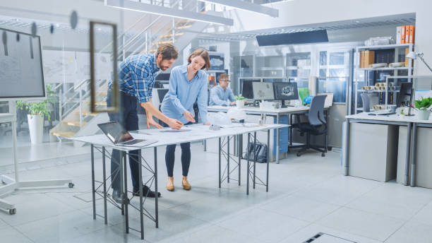 istock In the Busy Engineering Facility: Diverse Group of Engineers, Technicians, Working on Design for Industrial Engine Prototype. Specialists Talk During Meetings, Work with Drawings, Use Computers 1176843673