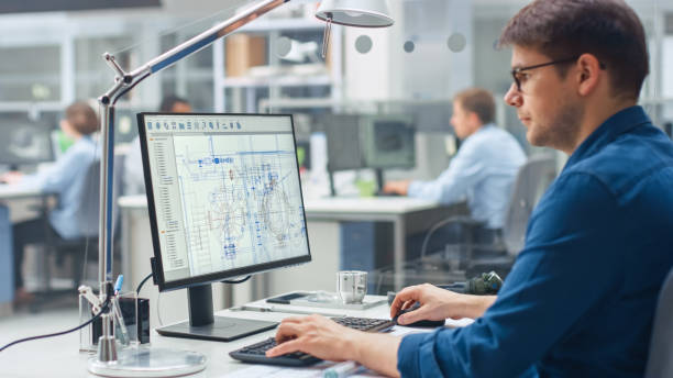 istock Over the Shoulder Shot of Engineer Working with CAD Software on Desktop Computer, Screen Shows Technical Drafts and Drawings. In the Background Engineering Facility Specialising on Industrial Design 1176843677