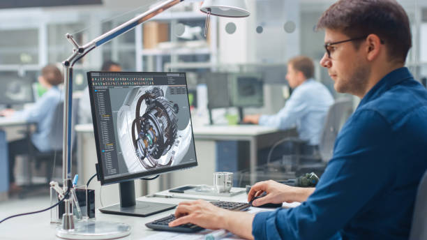 Over the Shoulder Shot of Engineer Working with CAD Software on Desktop Computer, Screen Shows Technical Details and Drawings. In the Background Engineering Facility Specialising on Industrial Design Over the Shoulder Shot of Engineer Working with CAD Software on Desktop Computer, Screen Shows Technical Details and Drawings. In the Background Engineering Facility Specialising on Industrial Design computer aided design stock pictures, royalty-free photos & images