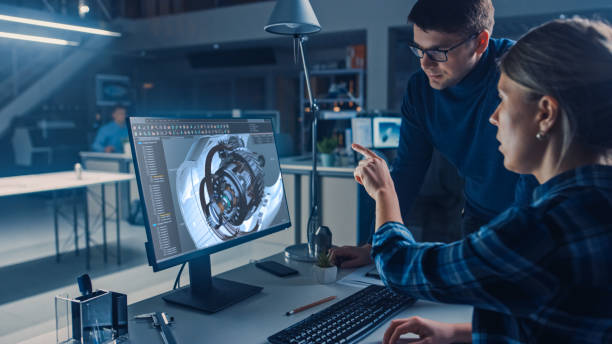 ingeniero que trabaja en computadora de escritorio, pantalla que muestra el software cad con el modelo 3d del motor, su gerente de proyecto masculino explica los detalles del trabajo. oficina de instalaciones de ingeniería de diseño industrial - ingeniería fotografías e imágenes de stock