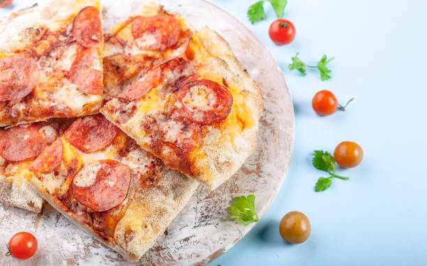 istock Closeup peperroni pizza on a cutting board on a blue background. Copy space 1176844409