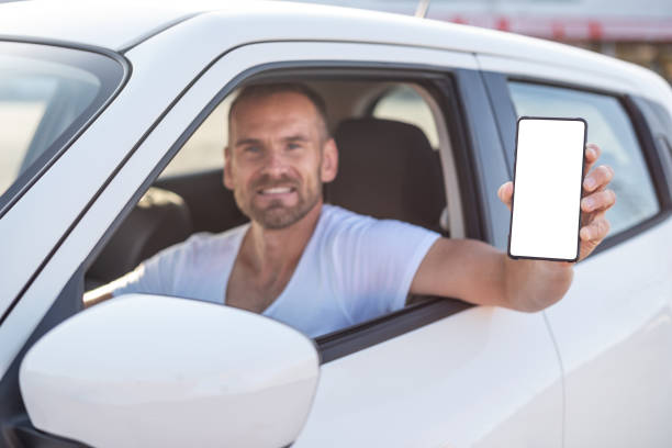 istock An attractive man in a car shows a smartphone. 1176847547