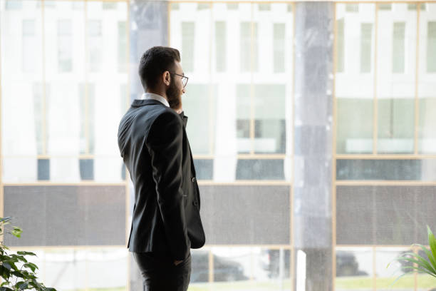istock Successful businessman talking on phone, standing near window in office 1176848520