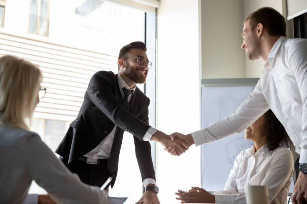 istock Smiling businessmen handshaking after successful group negotiations 1176848618